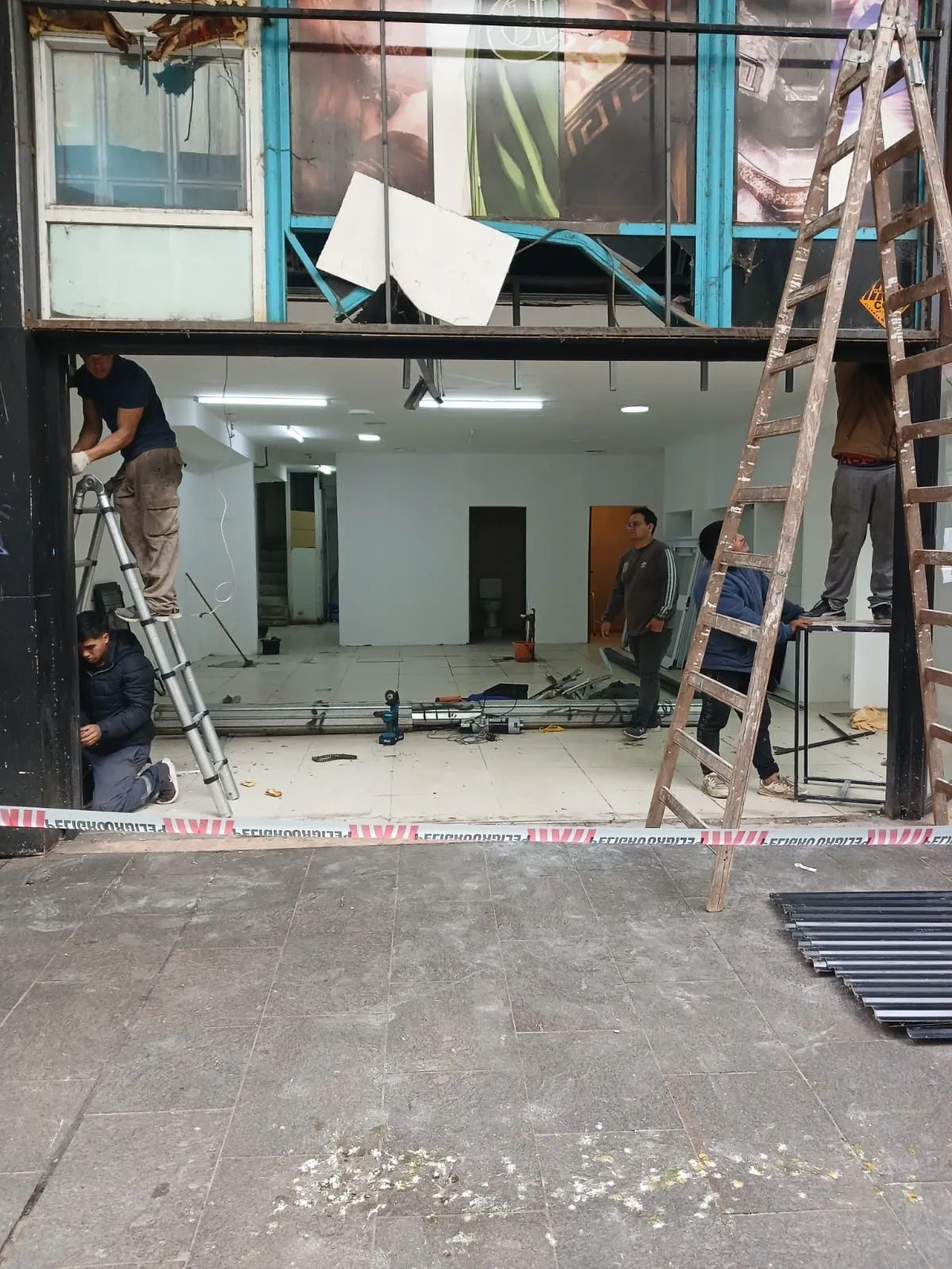 Equipo instalando una cortina metálica en un local comercial vacío
